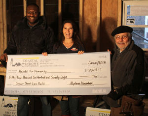 From left, Fredrick Otokunrin, who will live on the first floor of the house, Stephanie Vanderbilt, and Don Preston, president of Habitat for Humanity of the North Shore with the latest check for the Grover Street house in Lynn.