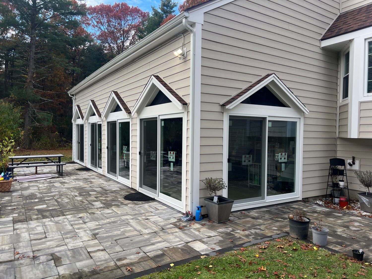 Exterior view of multiple Harvey sliding patio doors installed along a backyard patio, helping reduce outside noise while improving energy performance and usability.