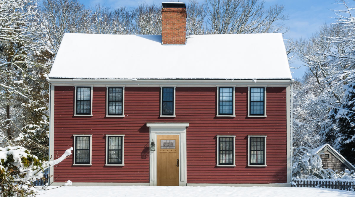 Ice dam formation on Essex County Massachusetts home showing how snow load on roof causes dangerous icicle buildup requiring professional roof inspection - Coastal Windows Beverly MA