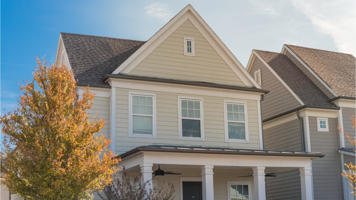 Beige lap siding and white trim on a two-story home with fall foliage, ready for winter siding installation season in Hamilton, North Shore.