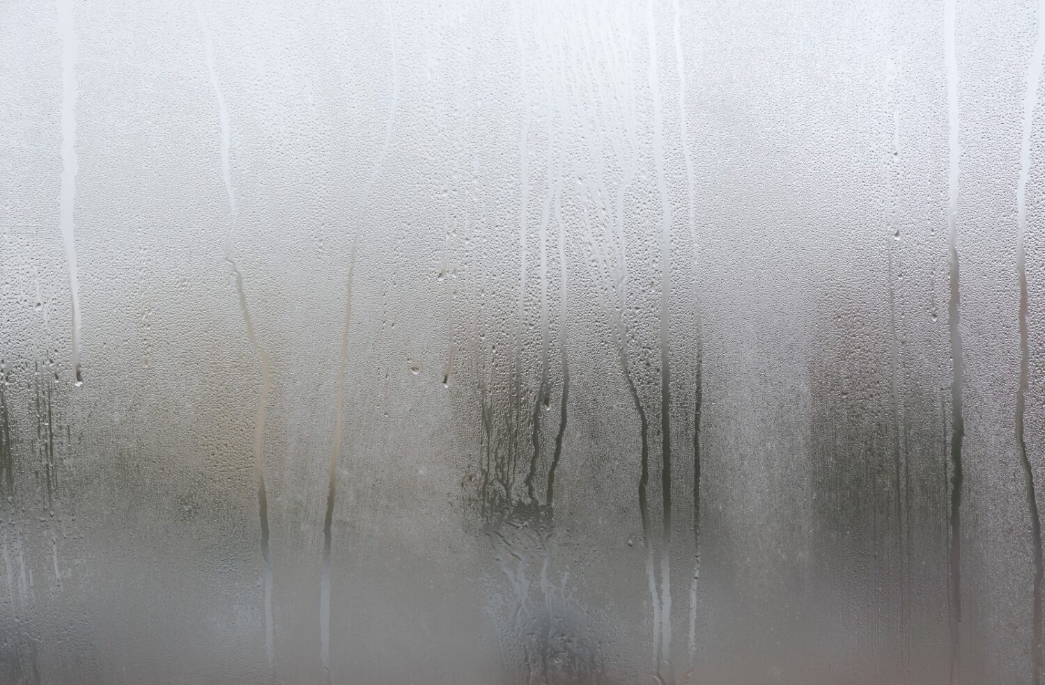 Foggy window glass covered in condensation and water droplets, a sign of window seal failure in Salem, North Shore.