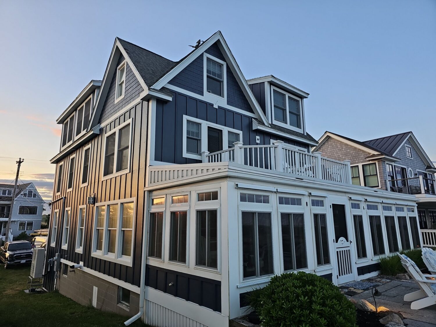 This coastal home showcases James Hardie siding in the popular Deep Ocean color, paired with crisp white trim and architectural details. Exploring James Hardie siding colors helps homeowners find bold, timeless options that complement New England homes.