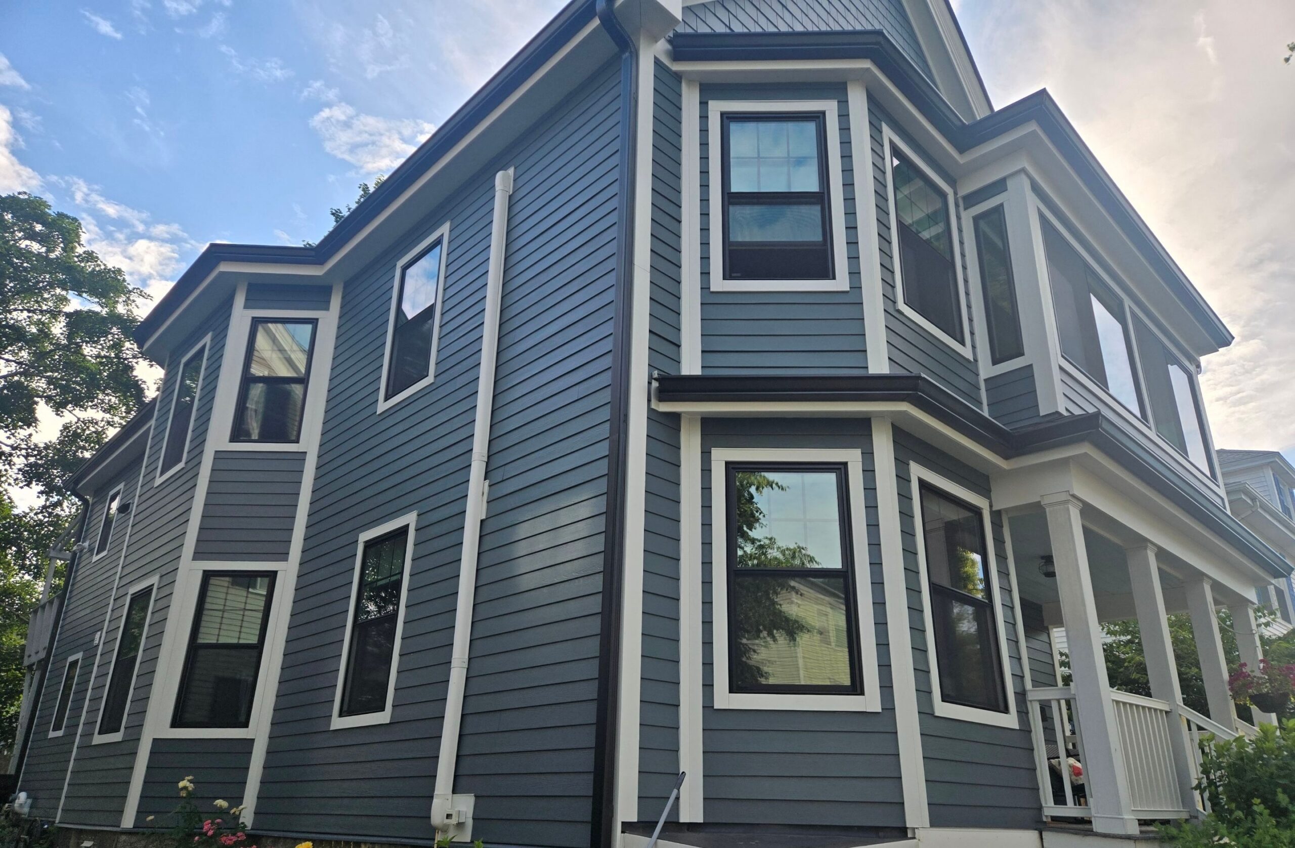 Modern blue home exterior with black-framed replacement windows designed for energy efficiency and summer comfort.
