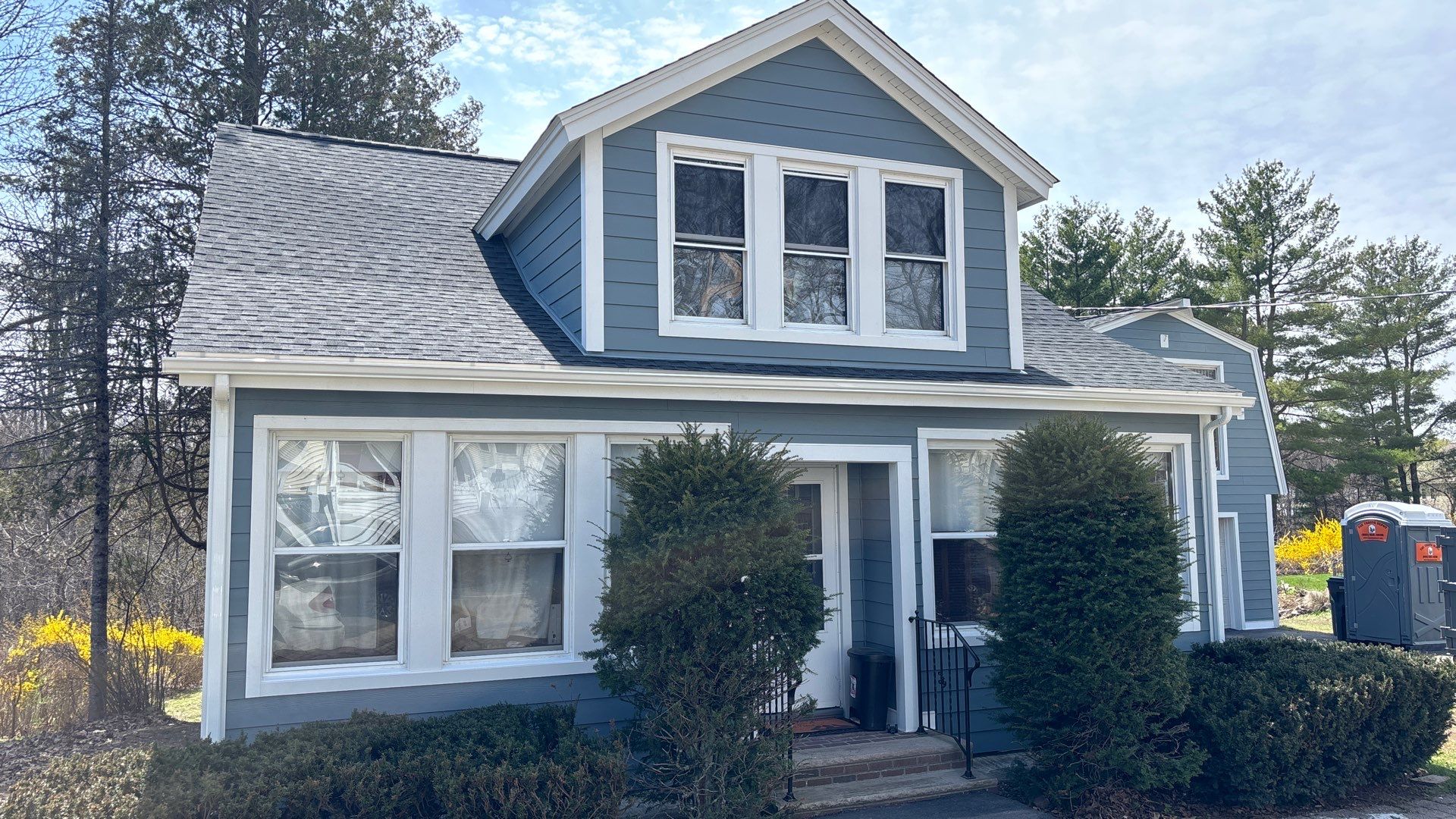 Newly installed replacement windows on blue home exterior designed to improve insulation and reduce summer heat transfer.