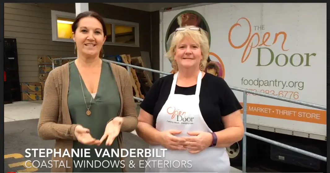 Two women stand outside near the Open Door Food Pantry truck in Gloucester. One wears a tan top, the other an apron. Text reads: Stephanie Vanderbilt, Coastal Windows & Exteriors.