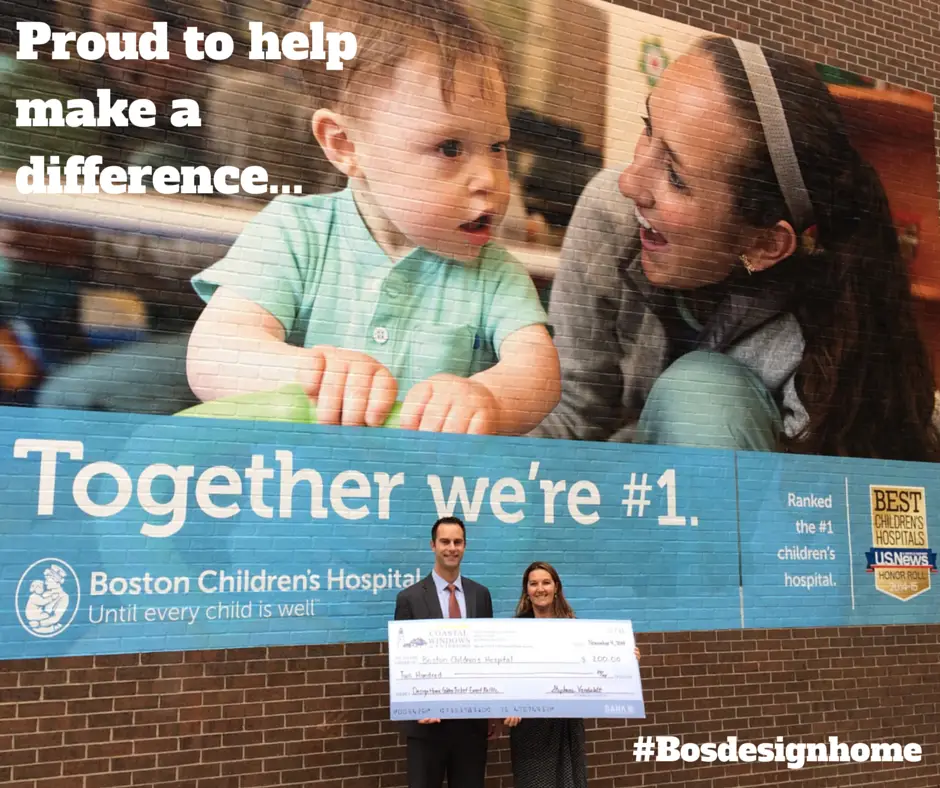 A man and woman hold a large check in front of a Boston Children’s Hospital mural featuring a baby and healthcare worker, with text: Proud to help make a difference... Together were #1. Coastal Windows & Exteriors supports this mission. Hashtag #Bosdesignhome is visible.