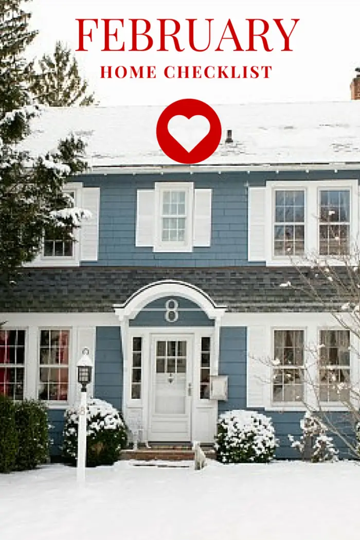Blue and white house with snow on the roof and yard, featured in the Coastal Windows & Exteriors Winter Newsletter. Text at the top reads February Home Checklist in red above a red heart icon. The house has the number 8 above the door.