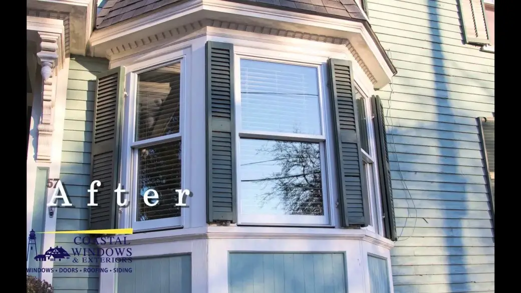 A bay window with green shutters on a blue historic home in Salem MA. The word After and the Coastal Windows & Exteriors logo appear in the lower left corner.