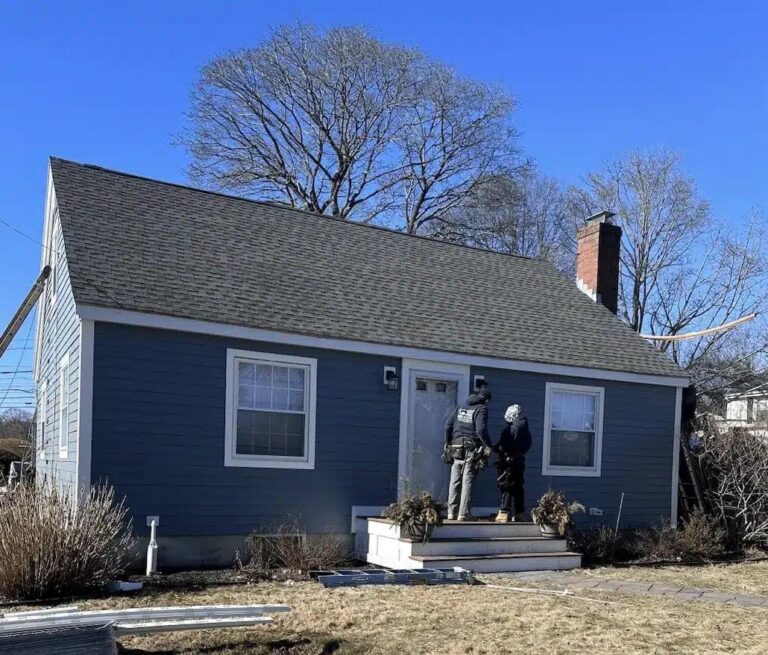 Homeowner discussing roof replacement options featuring one of the popular shingle colors for New England roofs on a blue exterior home.