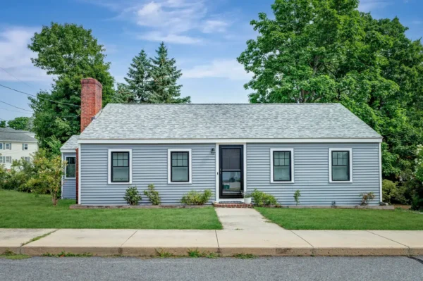 A finished Beverly home features gray siding, black-trimmed windows, a dark entry door, and a light asphalt shingle roof. This exterior demonstrates how a home maintenance checklist can cover roofing, siding, windows, doors, landscaping, and drainage around the entire property.