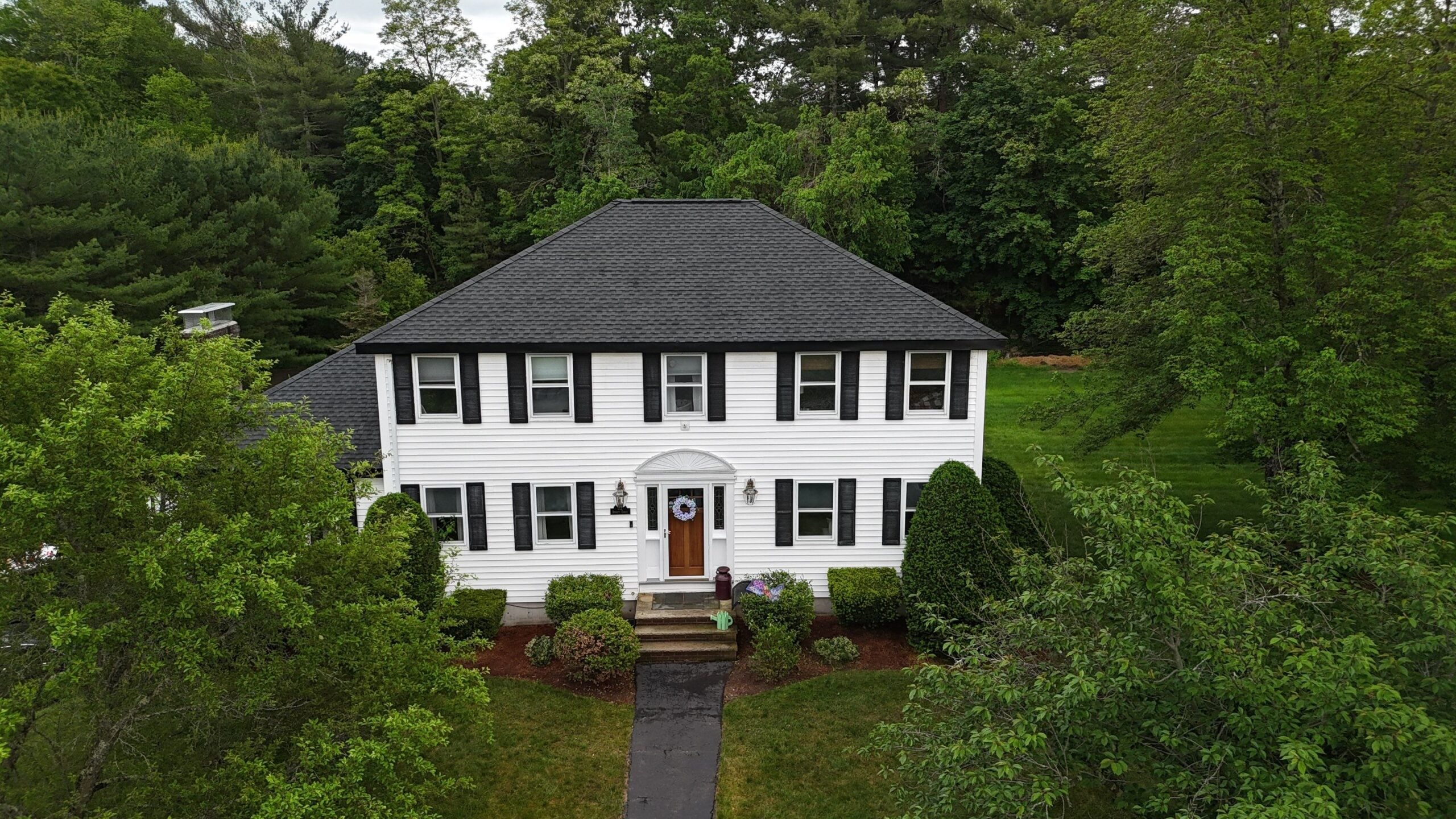 White Billerica MA home with asphalt shingle roof showing roofing as one of the top summer home exterior projects.