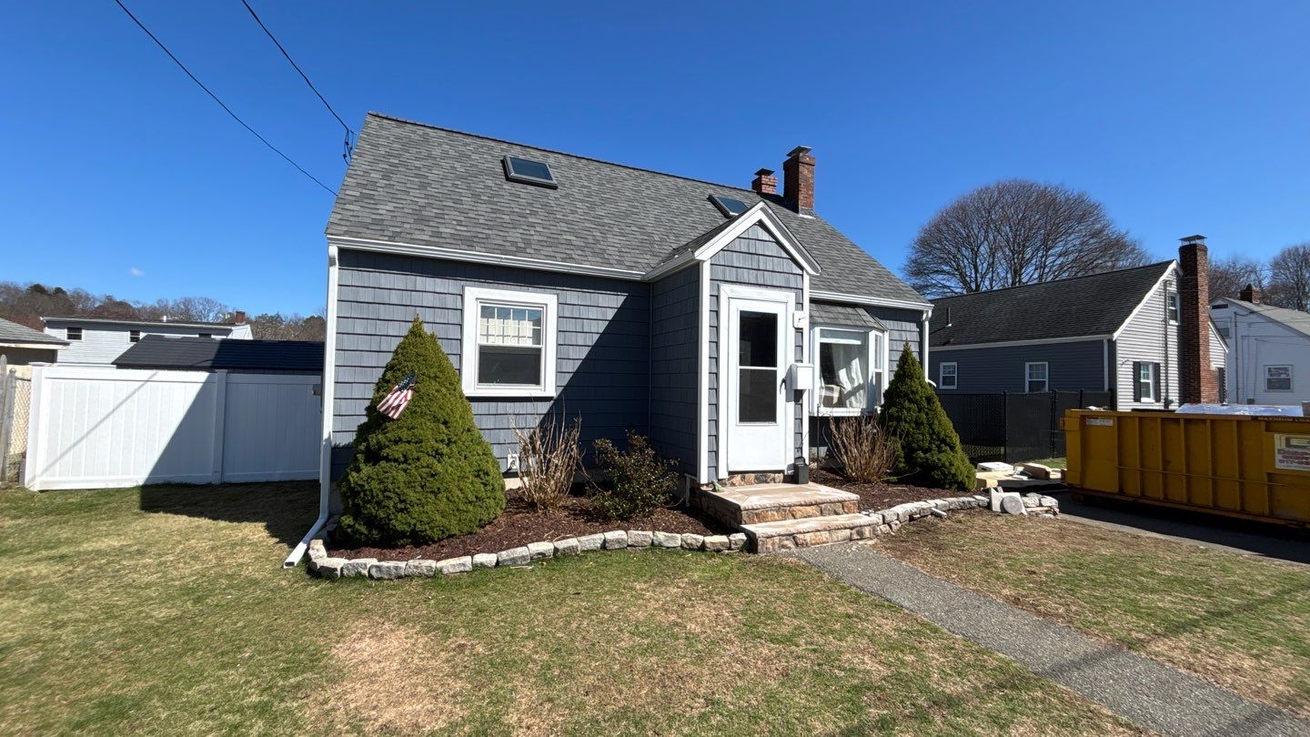 Renovated gray home with vinyl siding illustrating is it worth it to replace siding for a more attractive, low-maintenance exterior. Crisp white trim completes the updated residential design.