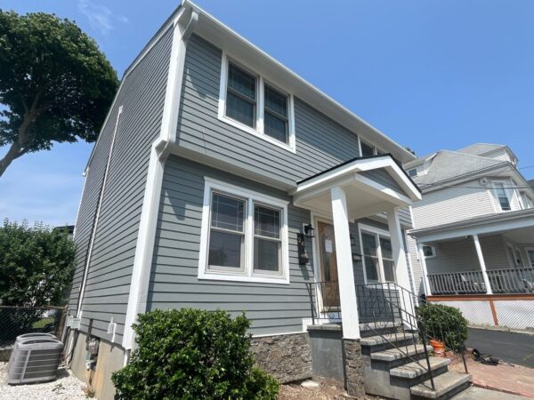 Modern home with gray siding demonstrating is it worth it to replace siding through enhanced appearance and long-term durability. White trim and updated exterior details create a clean finished look.