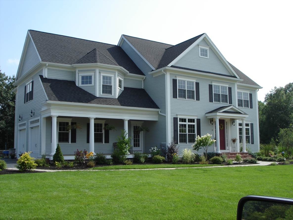 Dark asphalt shingles protect the rooflines of this blue home and coordinate with its white trim. A carefully completed roof installation in Bristol NH helps prevent water intrusion around valleys, eaves, and adjoining sections.