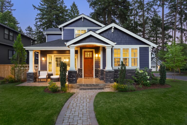 White-framed windows add symmetry and character to this gray Craftsman-style home at dusk. When insulated glass begins to fog, window contractors in Bristol NH can replace failed units and restore clear views.