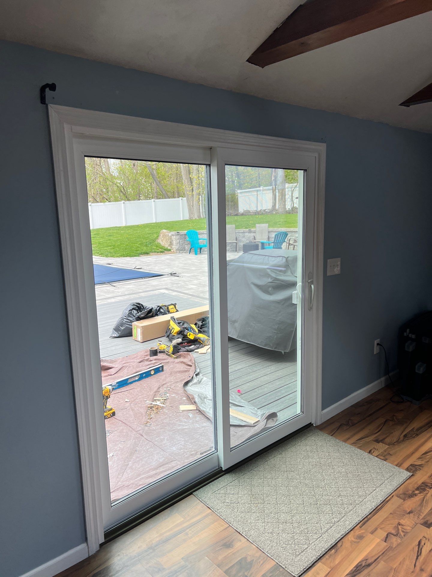 Clear glass panels in a crisp white frame now look out over the backyard patio, pool, and lawn from this blue-walled living room. Natural light pours in through these sliding glass doors installed in Danvers MA without letting the cold in.