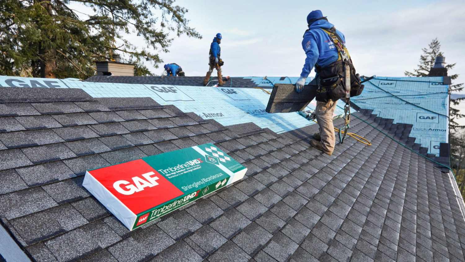 Roofing crew installing GAF Timberline UHDZ shingles on a home, representing exterior remodeling services by Coastal Windows & Exteriors in Beverly, MA.