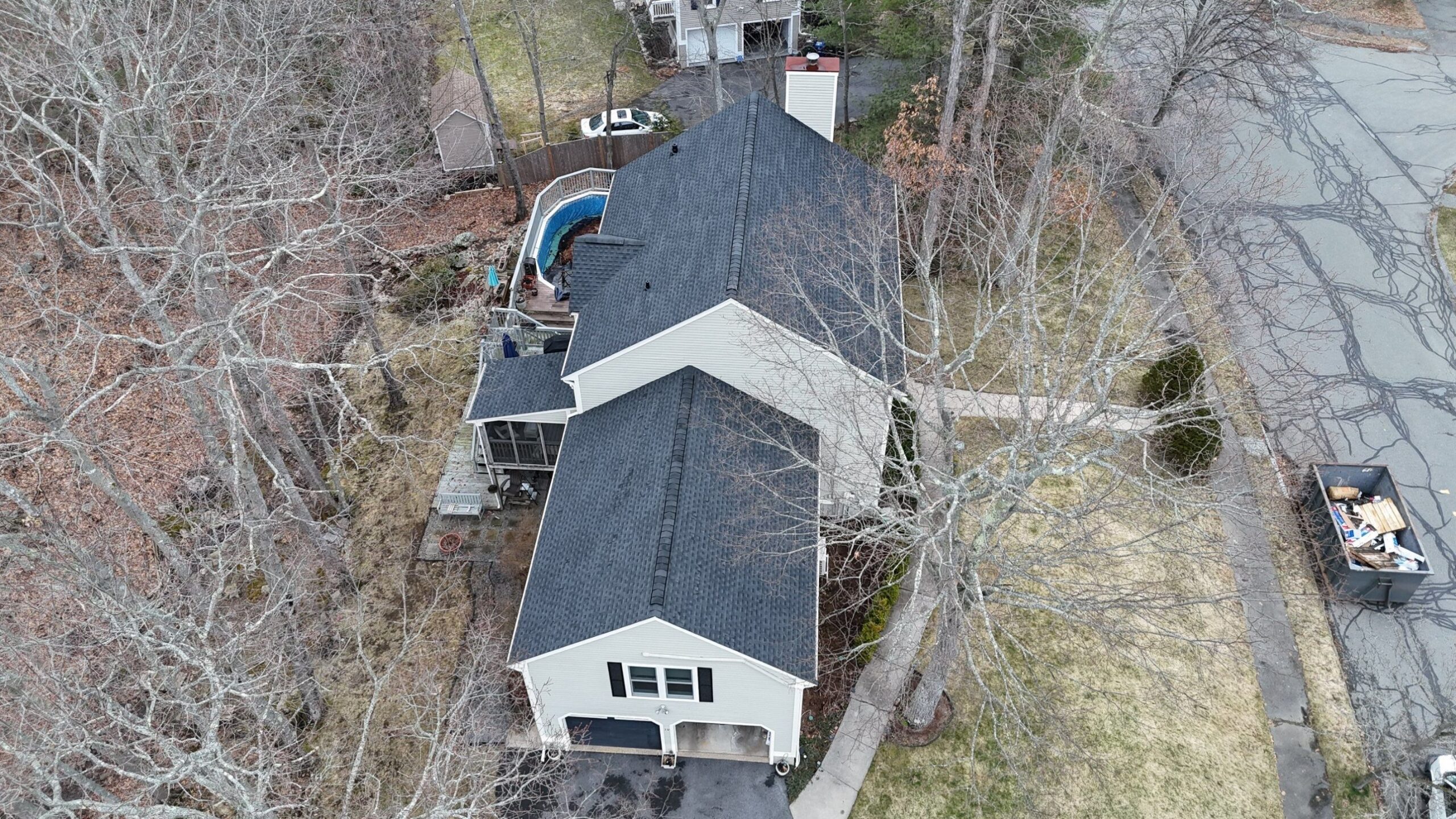 A drone view shows the entire new charcoal roof, with clean ridge caps across the main house, garage, and screened porch. Every worn shingle on this Beverly home was replaced by Coastal Windows & Exteriors, a trusted roofing contractor in Beverly MA.