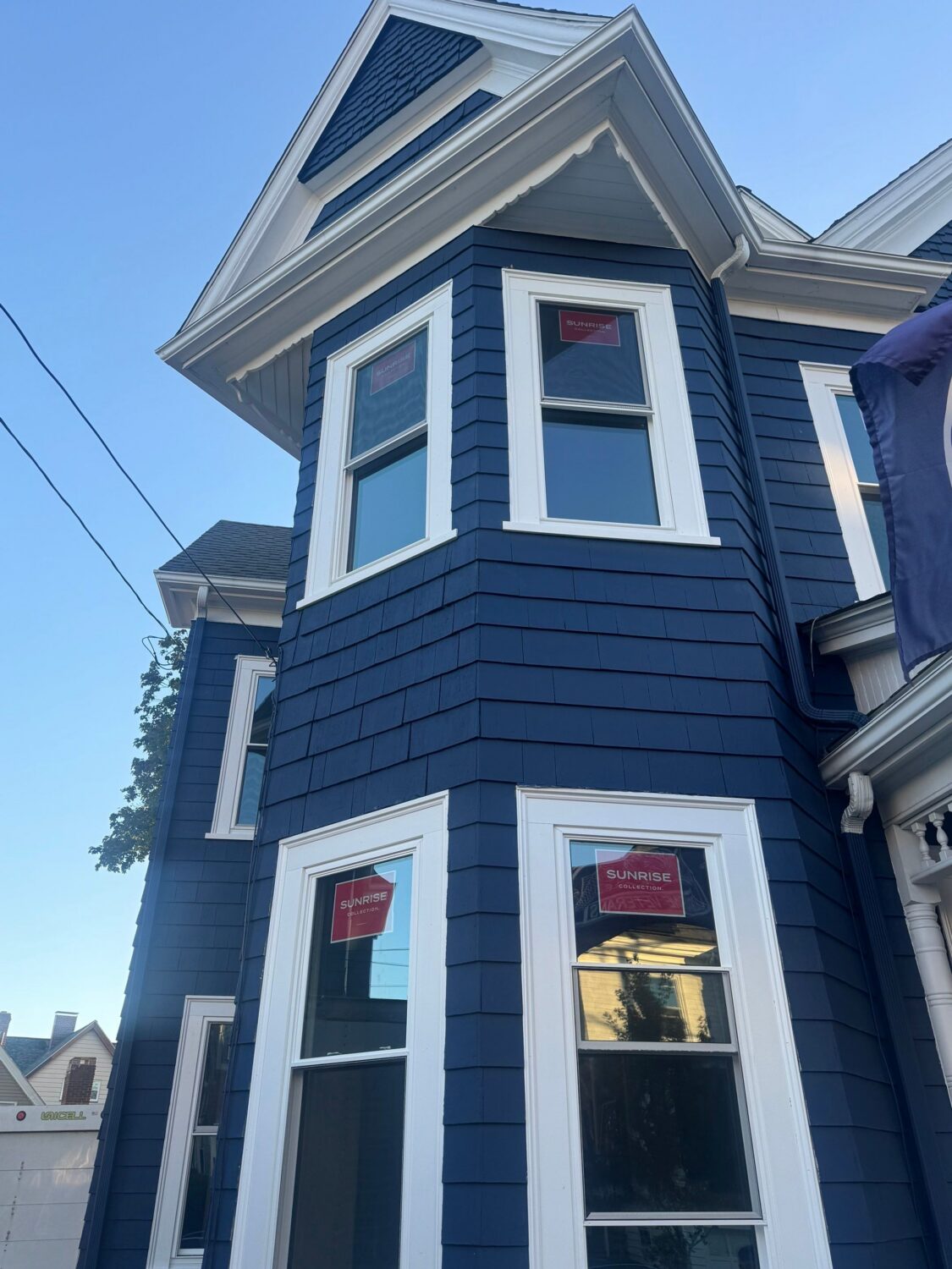 New vinyl double-hung replacement windows with white trim on a navy shingle Victorian bay in Everett, Greater Boston.