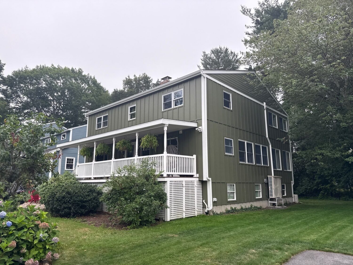 York, ME home with green board-and-batten siding, white trim, and a covered porch, a low-maintenance exterior refresh built around bundling exterior renovation projects.