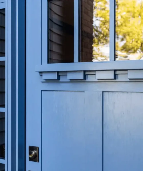 Close-up of a blue front door with glass panels and decorative trim.